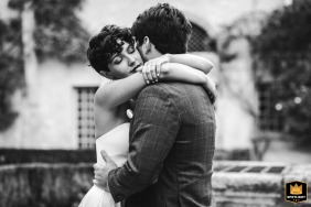 Bride tenderly embracing her husband in the courtyard of Mairie de Saint-Sever, Landes, France.